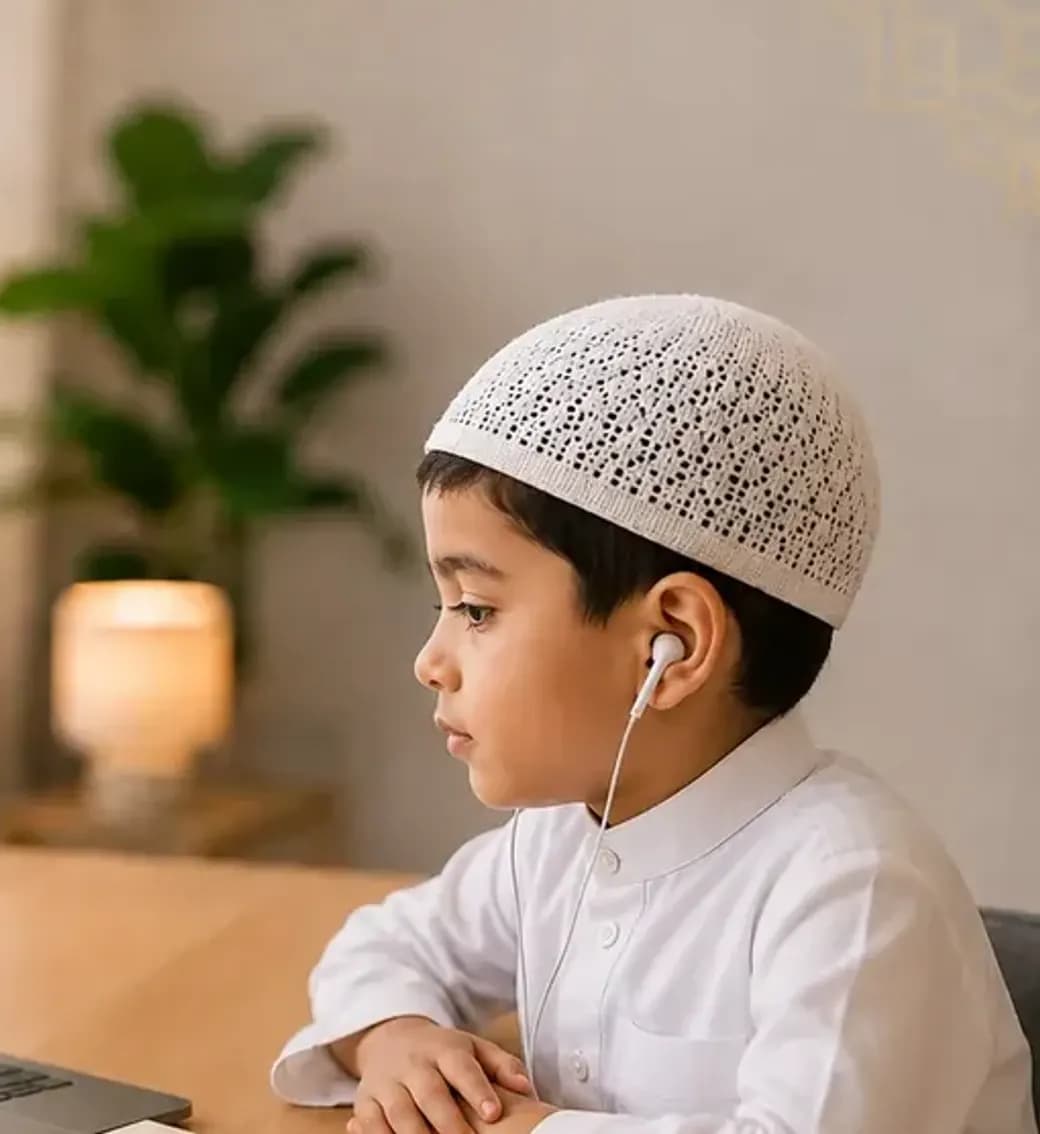 A boy follows a Noorani Qaida lesson on a laptop, with his teacher on screen